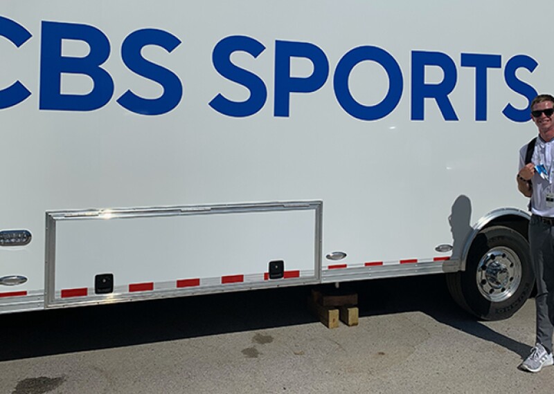 A man takes a picture outside a broadcast truck.