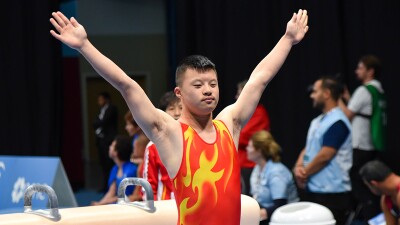 Young man with his arms up after finishing a gymnastics routine. 