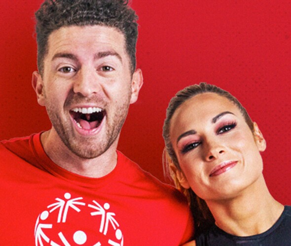 Dylan Landon flexing his bicep with his arm around Becky Lynch's shoulder. 