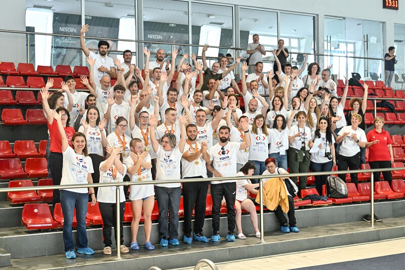 Group shot of people standing in the bleachers of a swimming pool