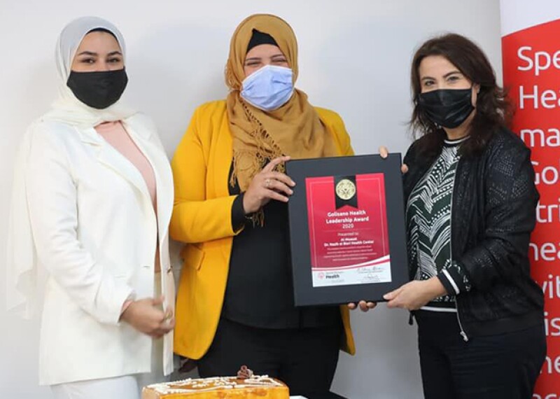 Two women receiving an award from another woman. 