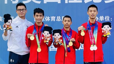 A coach with three athletes showing off their medals.