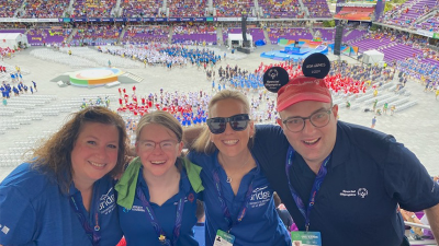 A group of four people pose for a photo in front of a large stadium. 