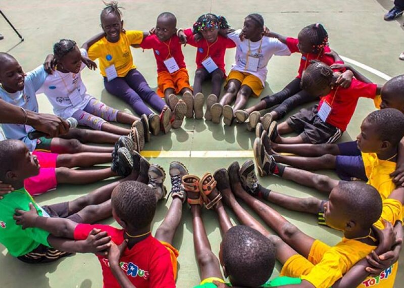 young athletes sitting in a circle with their feet together forming another circle. 