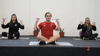 Three athletes sitting on a platform working out. 