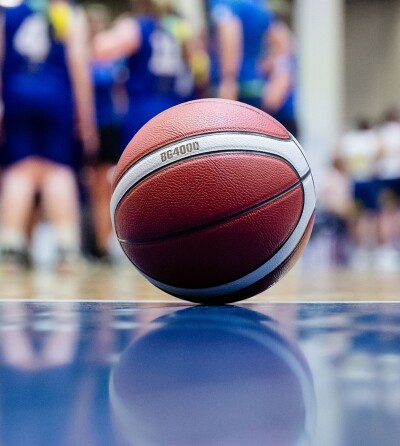 A basketball sitting on the court and the team is in the background. 