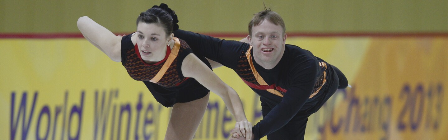 Female and male skating pair performing on the ice. 