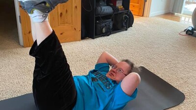 Athlete doing crunches on a yoga mat inside. 