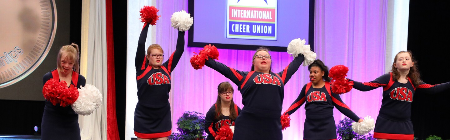 A group of young female cheerleaders cheering on stage. 