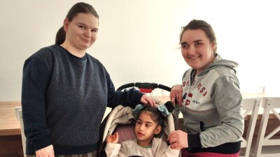 Olek and Vita stand posing for the camera with Rosa sitting in a stroller between them.