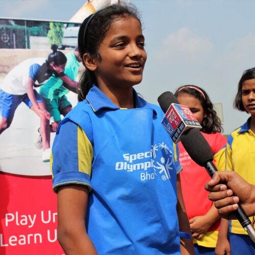 A young girl from Special Olympics Bharat speaks into a microphone during an event