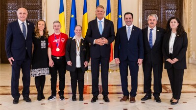 Group of people standing on either side of Romanian President Klaus Iohannis. 