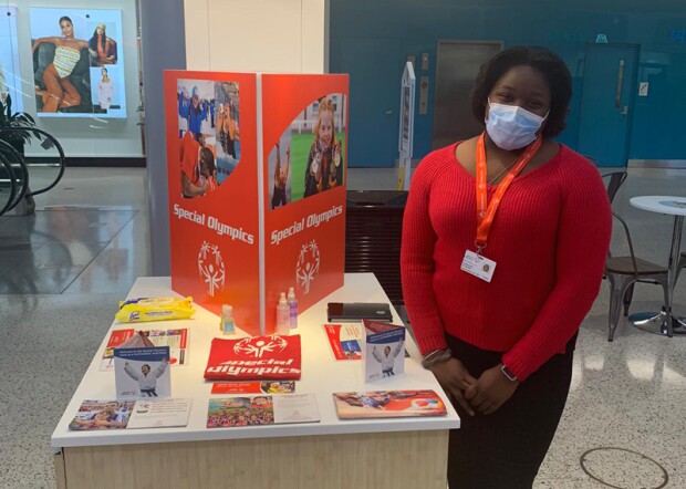 A canvasser standing at a table with Special Olympics branded materials. 