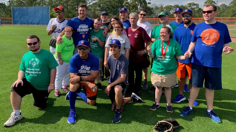 Group of New York Mets players and SO athletes on the field for a group photo. 