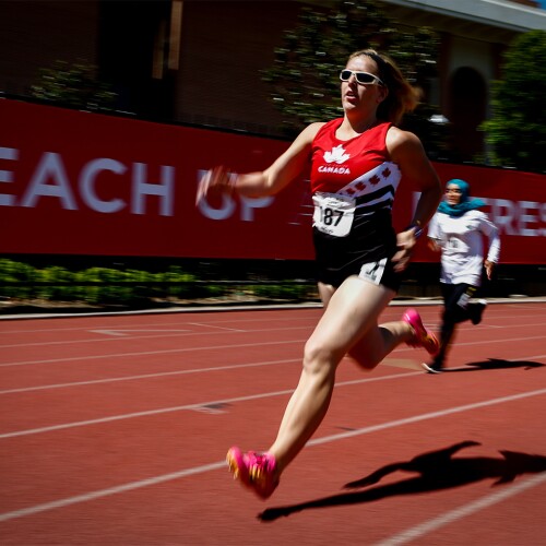 Female Canadian runner running on a track 