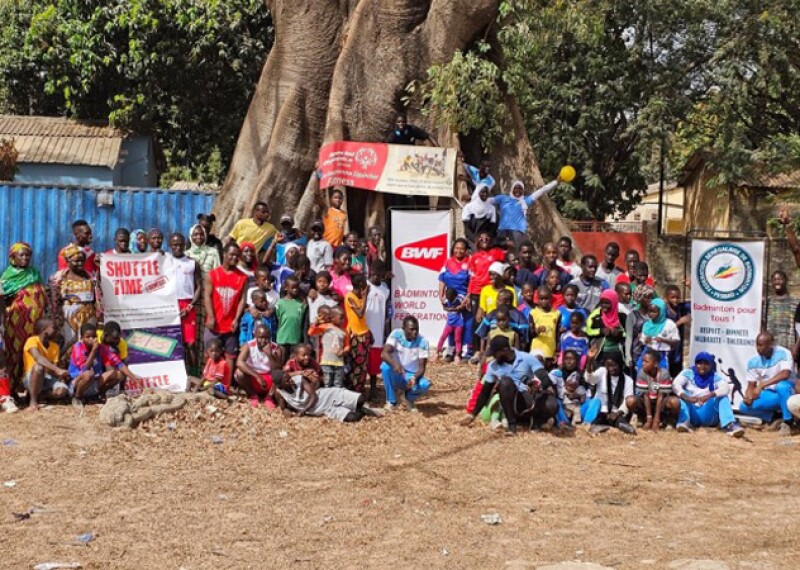 Large group of people standing in front of a tree. 