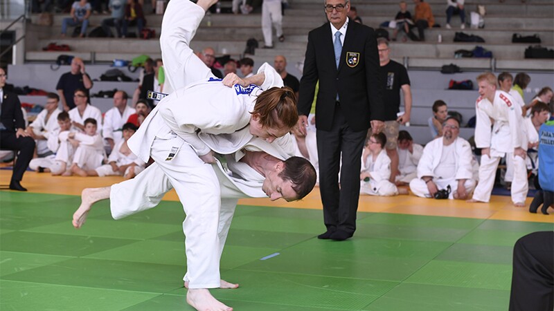 Two athletes competing. One athlete is flipping the other. 