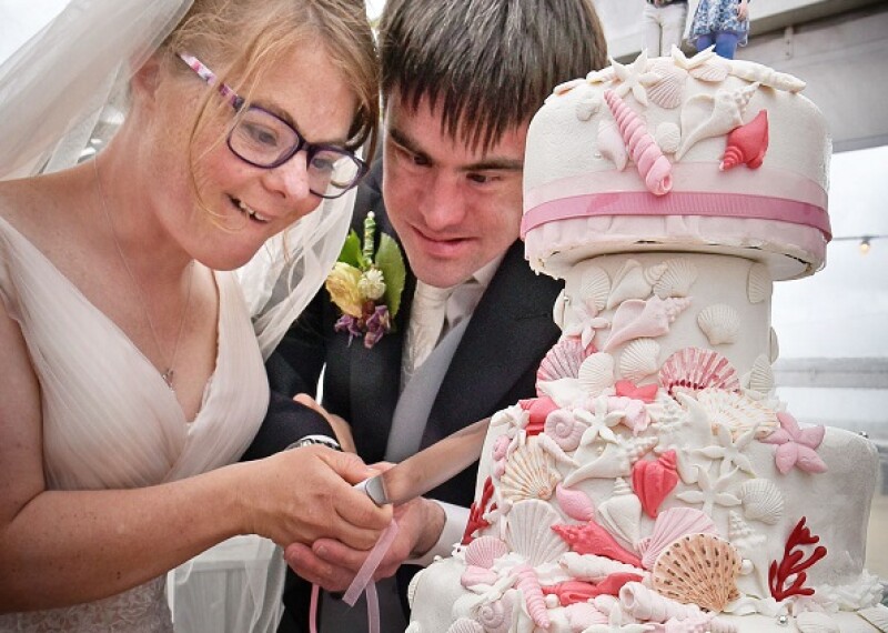 Two Special Olympics Athletes at their wedding cutting cake