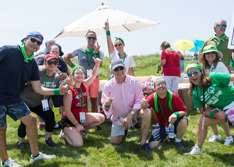 group of people outside on a grassy field standing close for a group picture. 