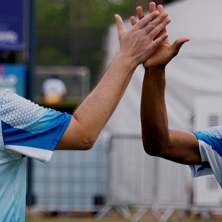 Two athletes giving one another a high 5.