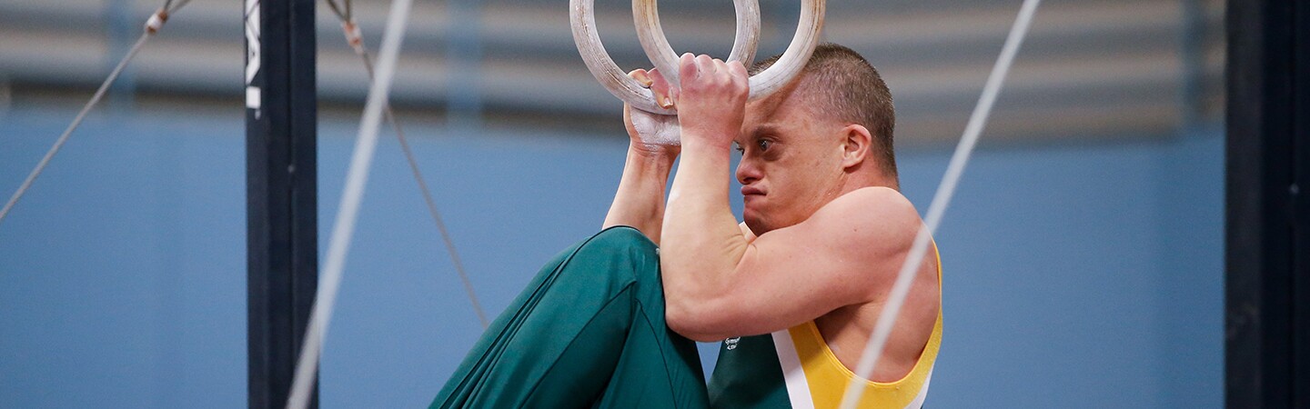 Male athlete tucking on the rings