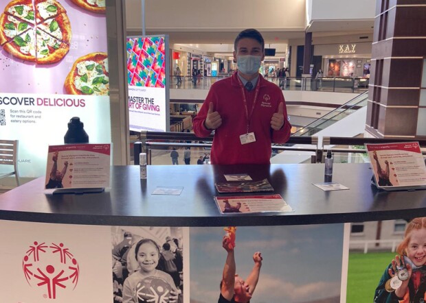 A canvasser standing at a table with Special Olympics branding.