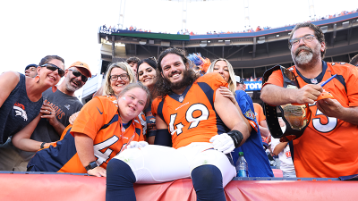 A group of people pose for a photo. Alex Singleton is in the front wearing an NFL uniform. 