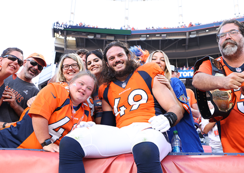 A group of people pose for a photo. Alex Singleton is in the front wearing an NFL uniform. 