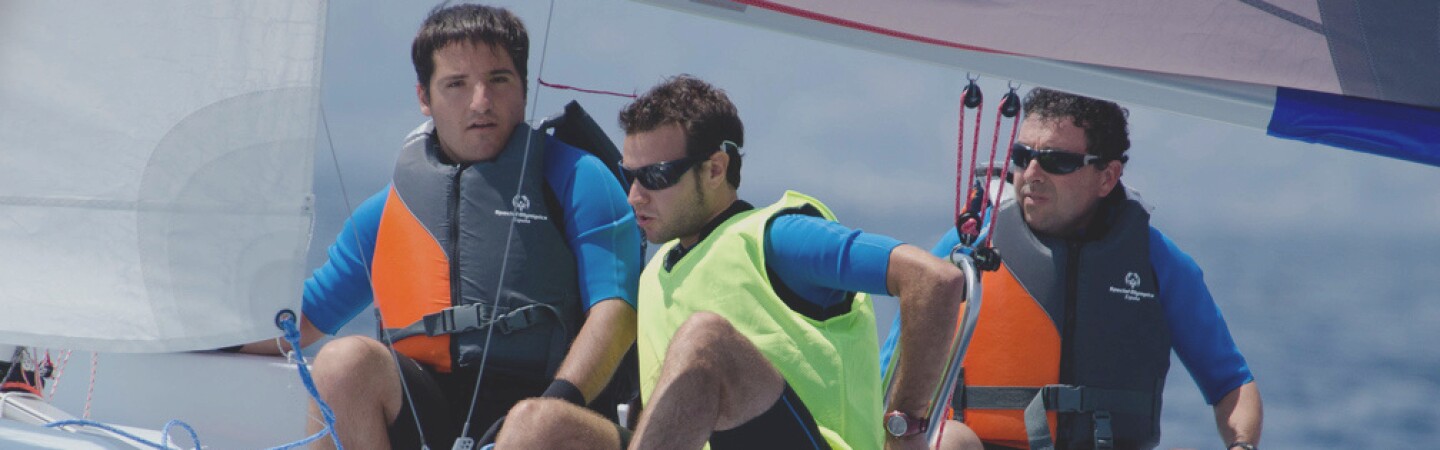 Athlete sailing while his team assists. 