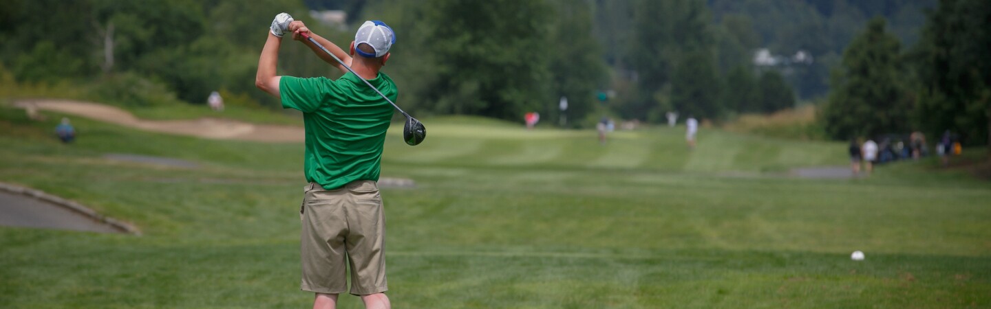 A male golfer just after striking the ball. 