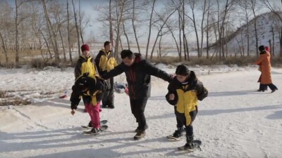 An adult is assisting younger athletes run in the snow. 