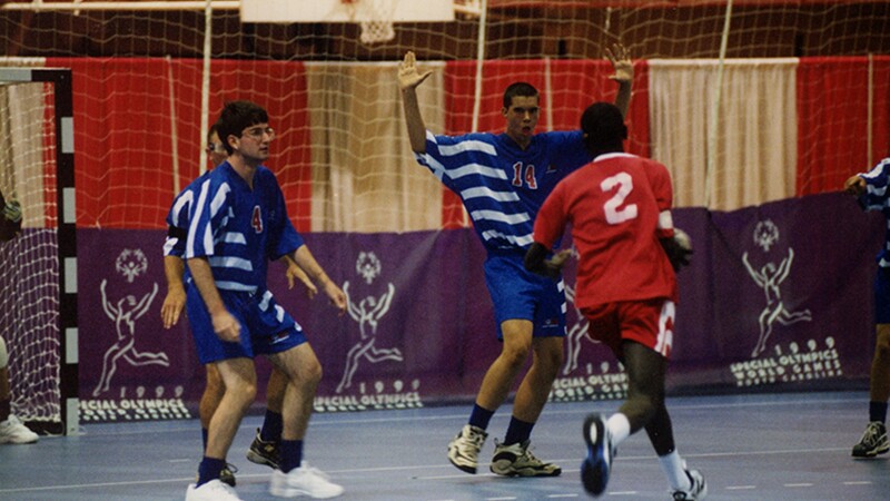 One player dribbling the ball going for the basket while a player from the opposing team attempts to block him. 