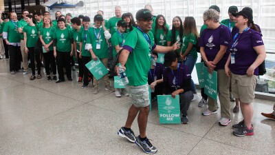 United Airlines volunteers wearing green t-shirts line up inside an airport.