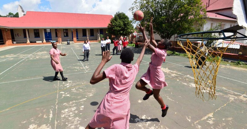 Female athletes practice netball on the court. 