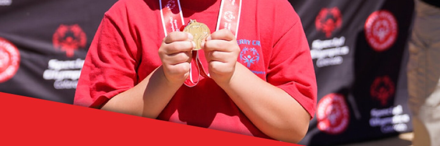 Young boy showing off his gold medal and smiling. 