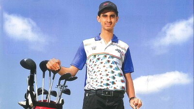 Young man standing next to golf clubs. 