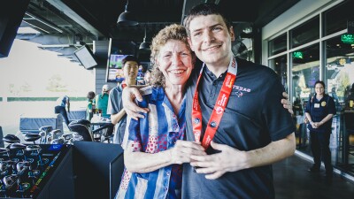 Woman standing with a young man at a topgolf facility.