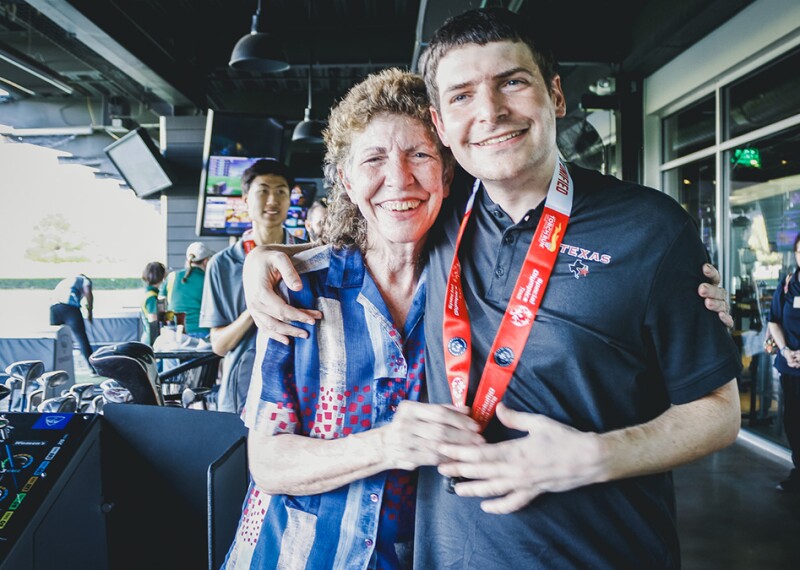 Woman standing with a young man at a topgolf facility.