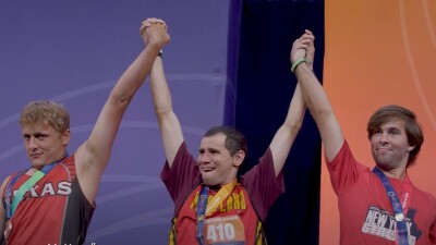 Thee men holding hands and raising them in the air in victory. 