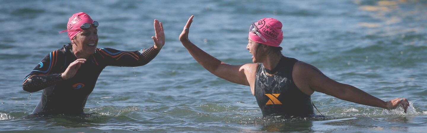 Two female players give one another a high-5 as they come out of the water. 