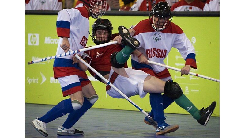 Three players on the floor during a floor hockey game. 