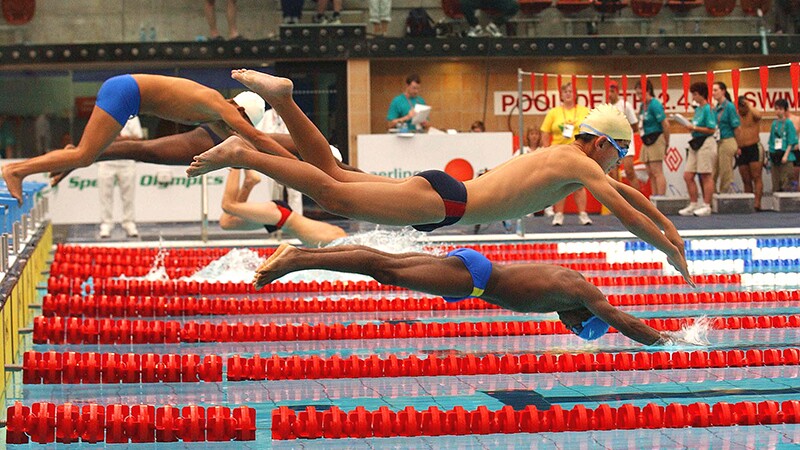 Athletes at a swim meet are diving into the water. 