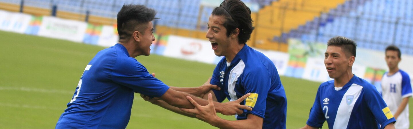 Three young man celebrate on the soccer pitch. 