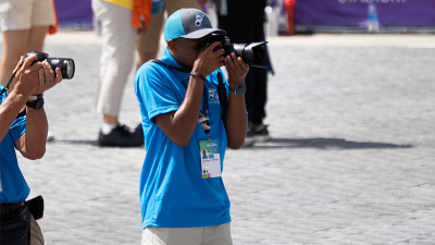 A Special Olympics athlete holds a professional camera and takes a photo. 