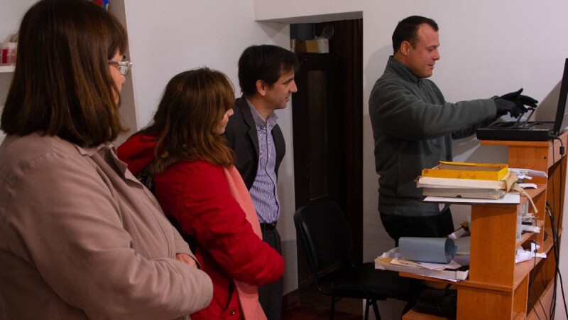 Pablo Composto shows two women and a man, representatives of the Villa Elisa Municipality, details about his work and the machines he uses in the El Porvenir Museum