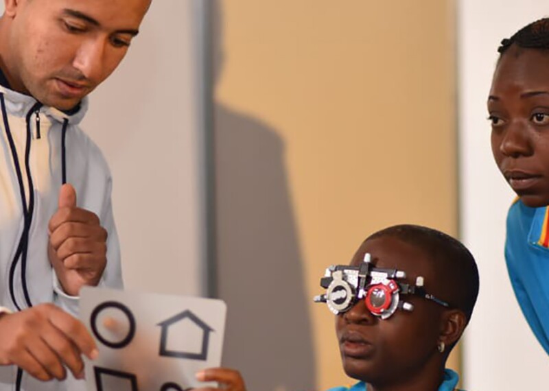 Athlete being given an eye exam by a volunteer and an observer watching. 