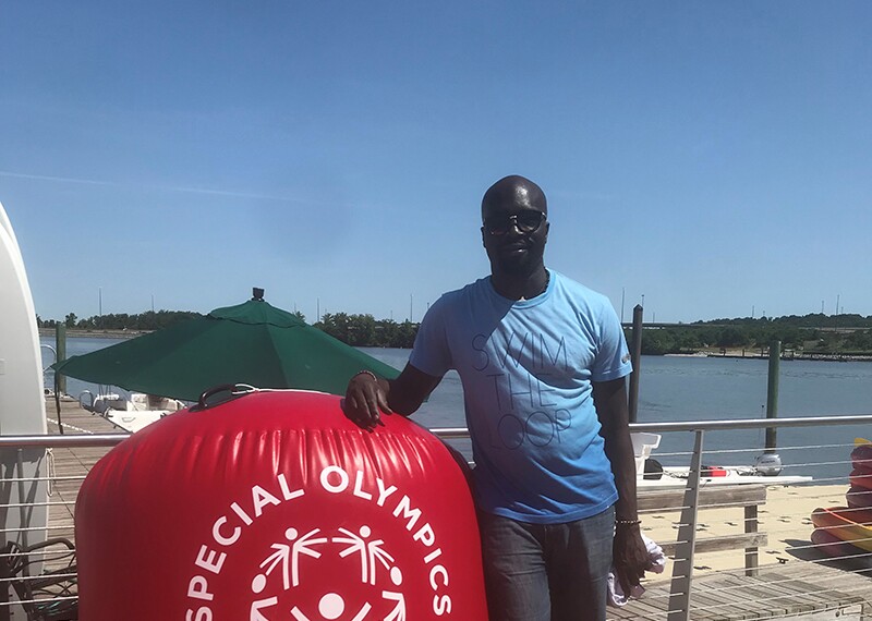 Kester Edwards standing on the dock, next to a Special Olympics Play Unified float.