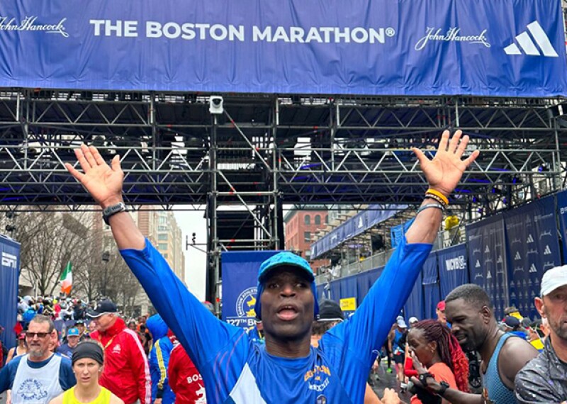 Trent Hampton with arms up in the victory pose above his head after crossing the finish line 