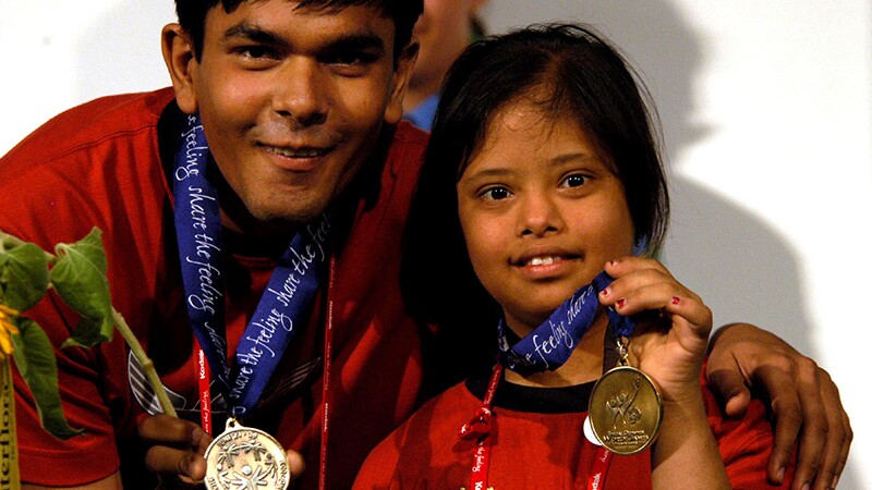 Two athletes—one male and one female—are showing off their medals. 