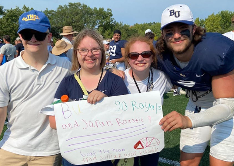 Three Special Olympics athletes hold a sign supporting Jaran Roste (on the right).